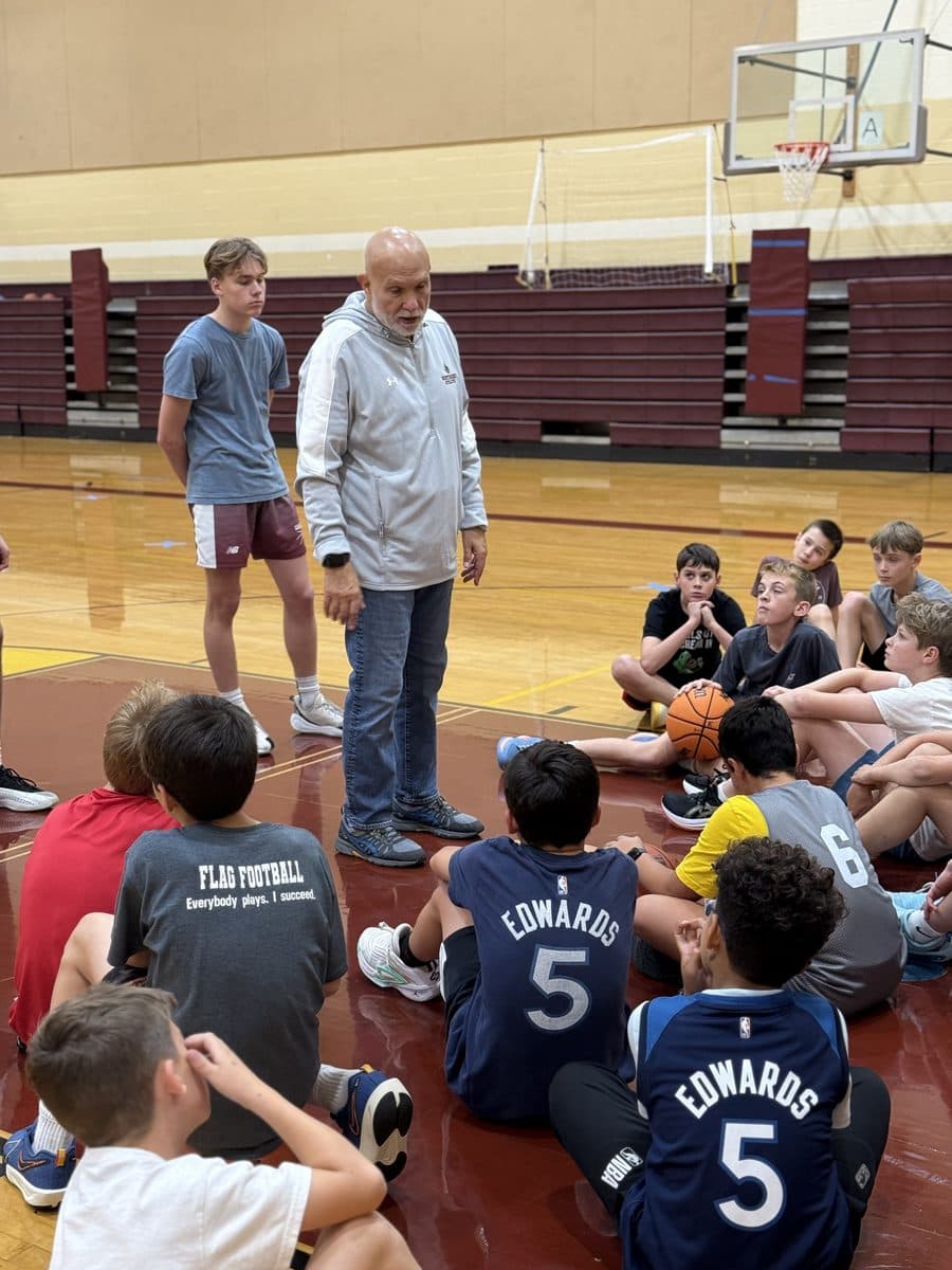 Coach Will Rey talking to Jr Knights players seated on the court at Northridge Prep